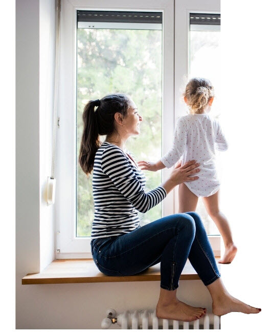 Mother and daughter looking out of a window.