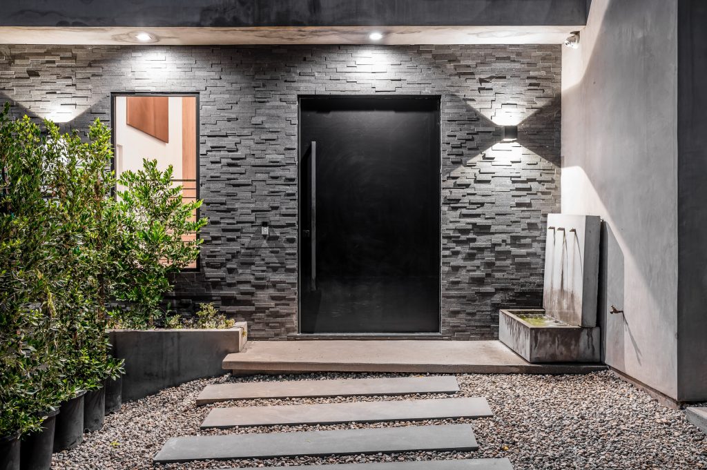 entrance and entryway lighting at night and plants surrounding it